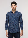 Man wearing a blue blue floral printed denim shirt on a light gray background