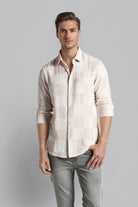 Man wearing a patterned shirt and gray pants on a gray background