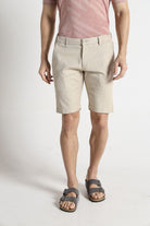 Person wearing beige shorts and a pink shirt on a white background