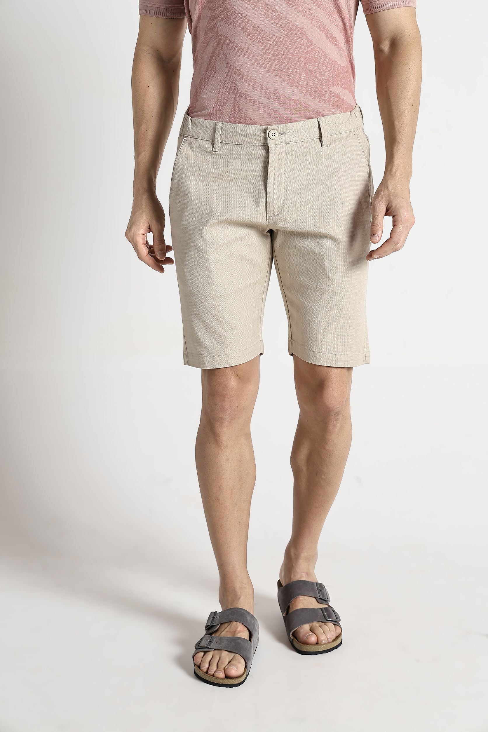 Person wearing beige shorts and a pink shirt on a white background