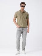 Man wearing a olive light olive structure comfort fit polo t shirt on a light gray background