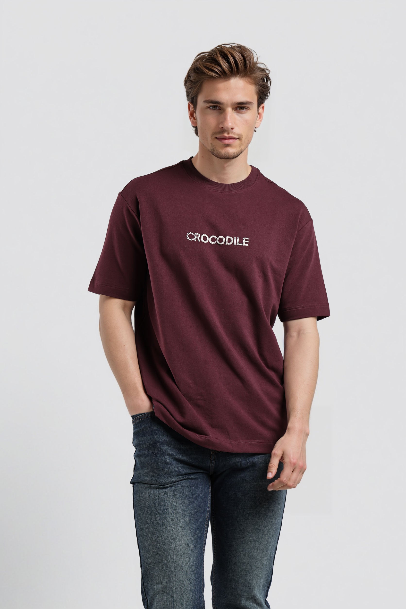 Man wearing a maroon t-shirt with a logo on a light gray background