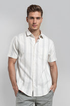 Man wearing a white striped shirt and gray pants on a gray background