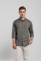 Man wearing a gray checkered shirt and white pants on a light gray background