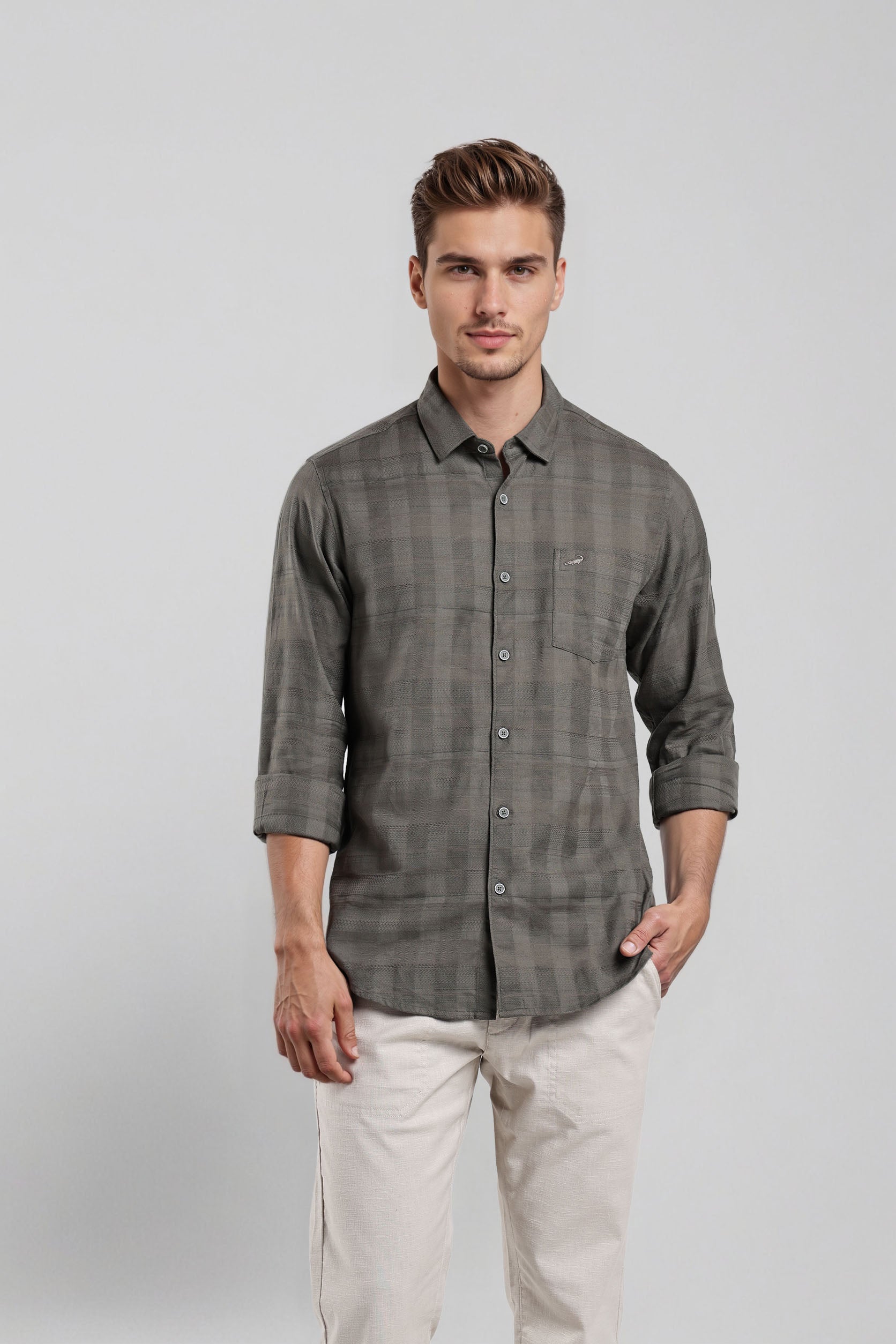 Man wearing a gray checkered shirt and white pants on a light gray background