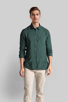 Man wearing a green shirt and beige pants against a gray background