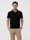 Man wearing a black black solid slim fit polo t shirt with casual styling on a gray background