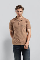 Man wearing a brown polo shirt with a small logo on a light gray background