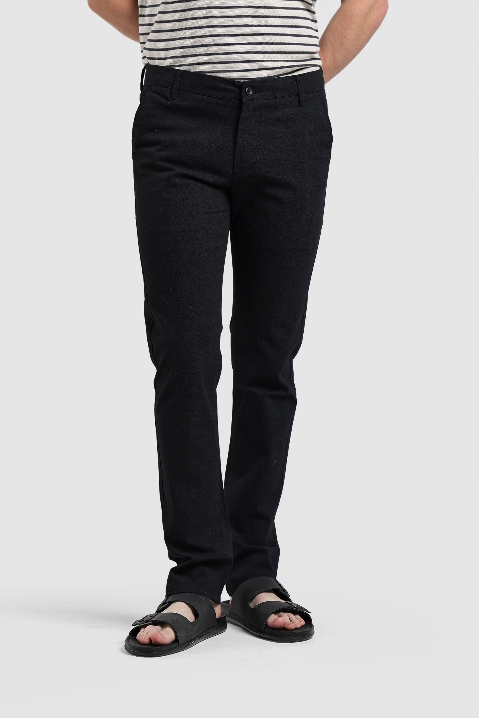 Person wearing black pants and a striped shirt on a white background