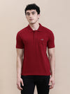 Man wearing a red brick red solid polo t shirt with pocket with casual styling on a gray background