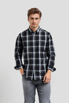 Man wearing a black and gray plaid shirt on a light gray background