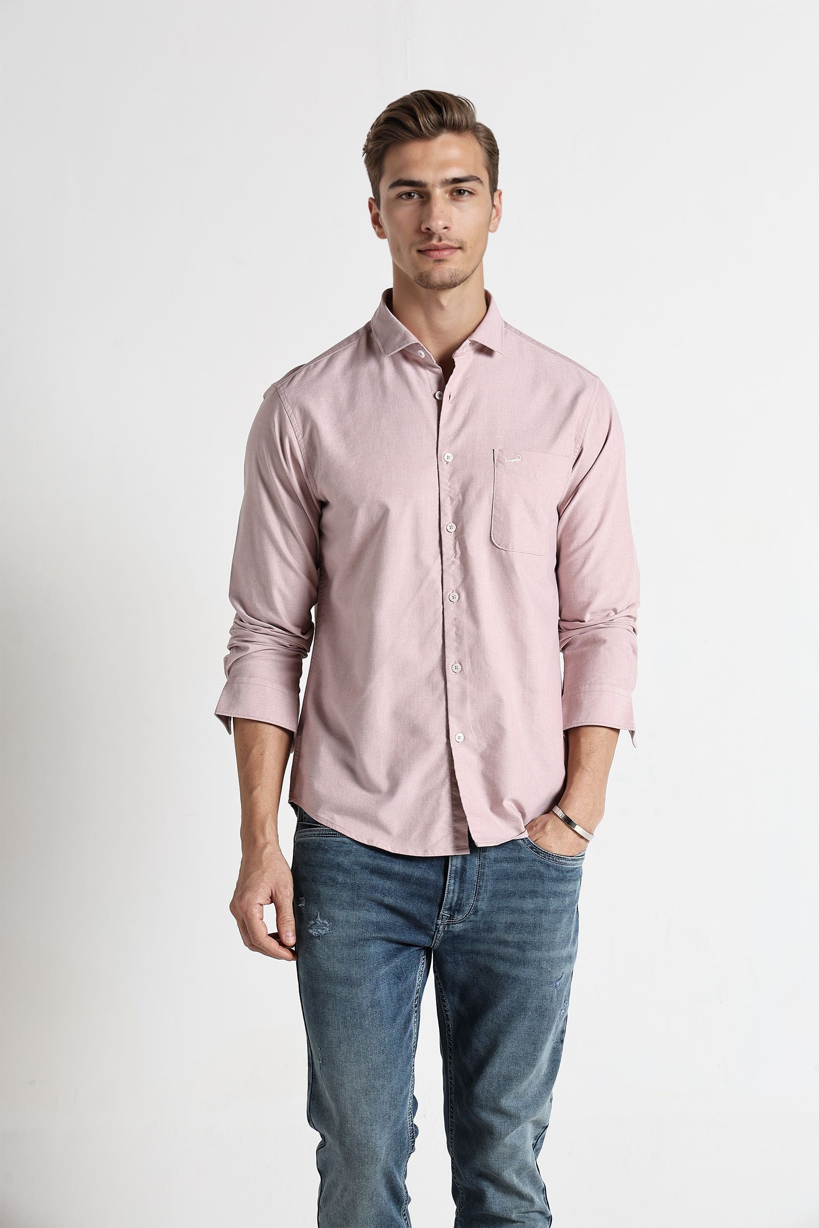 Man wearing a light pink shirt and blue jeans on a white background