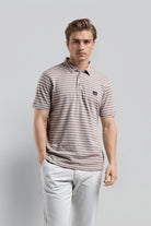 Man wearing a striped polo shirt and light pants on a gray background