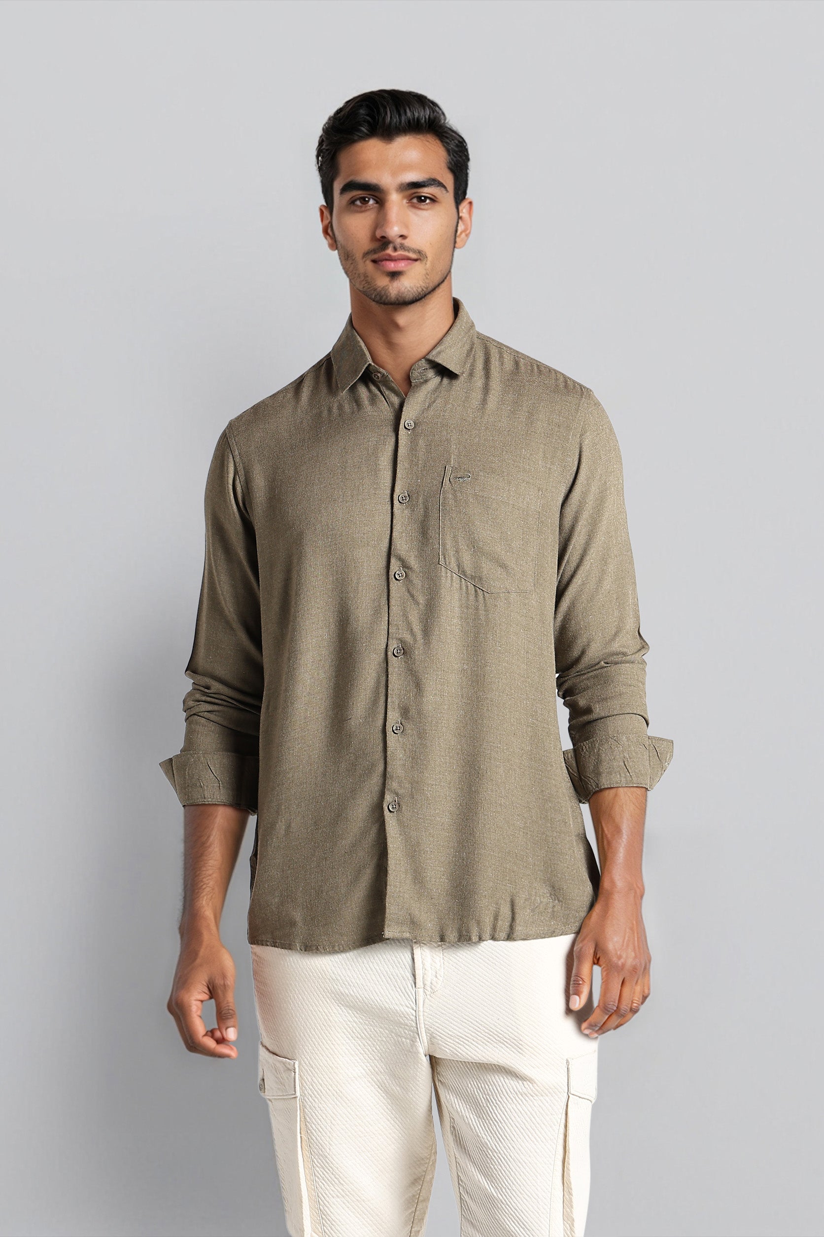 Man wearing a green shirt and white pants against a gray background