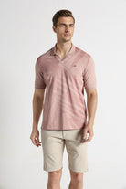 Man wearing a pink polo shirt and beige shorts on a white background