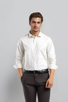 Man wearing a white dress shirt and dark pants against a gray background