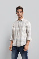 Man wearing a plaid shirt and jeans against a gray background