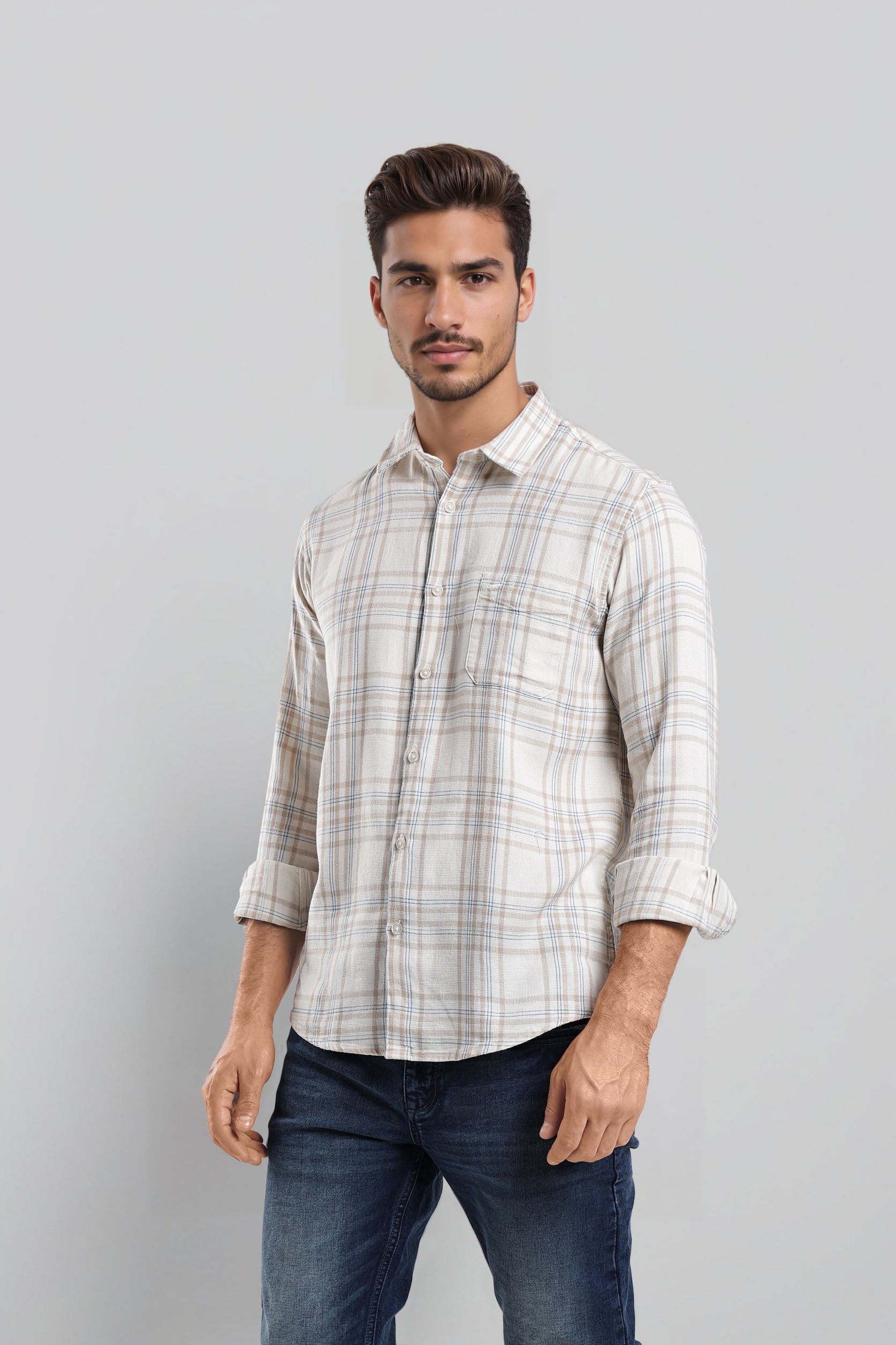 Man wearing a plaid shirt and jeans against a gray background