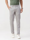 Man wearing a grey light grey solid slim fit trousers with casual styling on a gray background