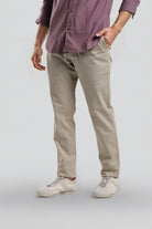 Person wearing a purple shirt and beige pants on a plain background