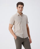 Man wearing a beige pure cotton textured shirt beige on a light gray background