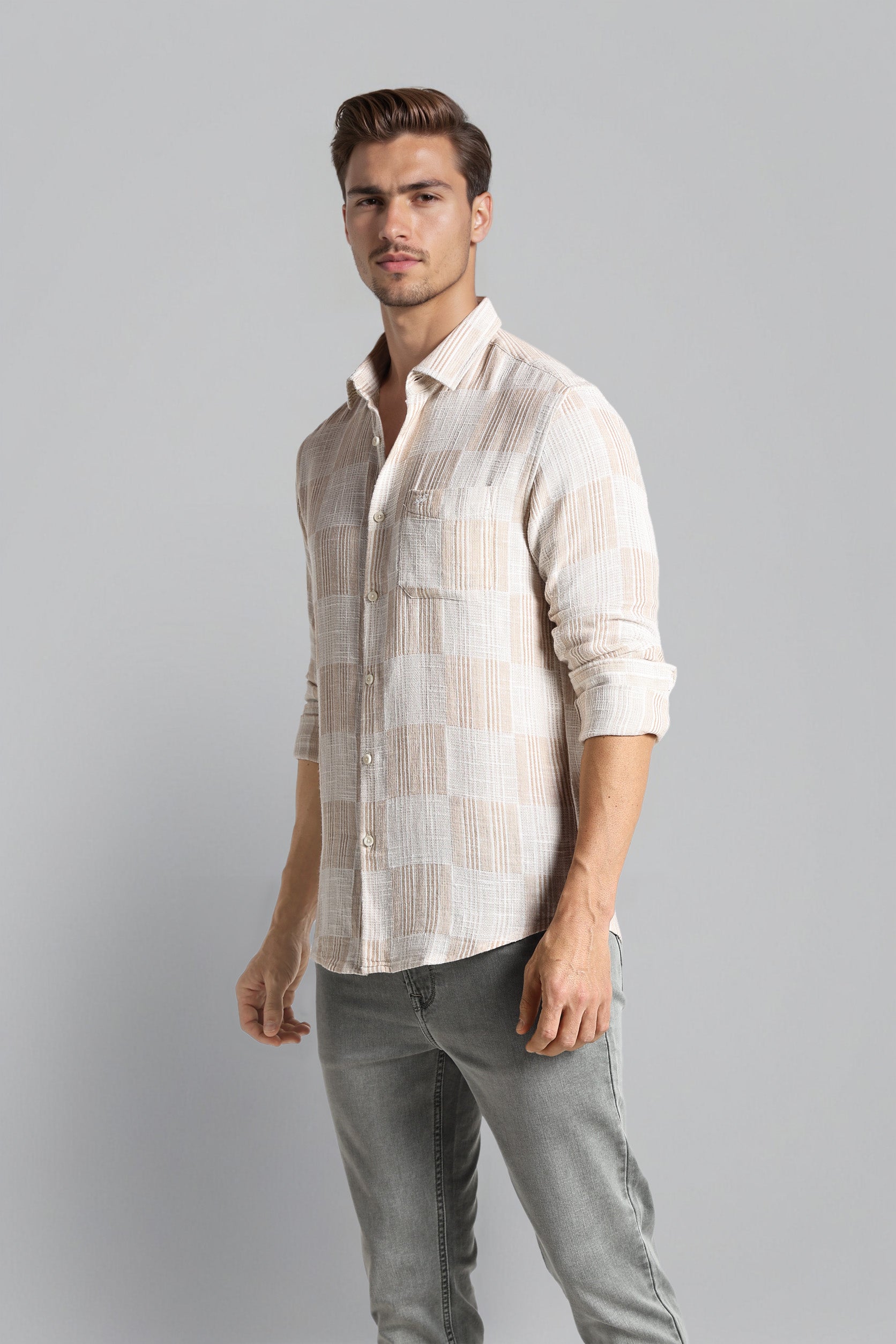 Man wearing a light-colored checkered shirt and gray pants on a gray background