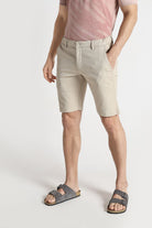 Person wearing beige shorts and a pink striped shirt on a white background