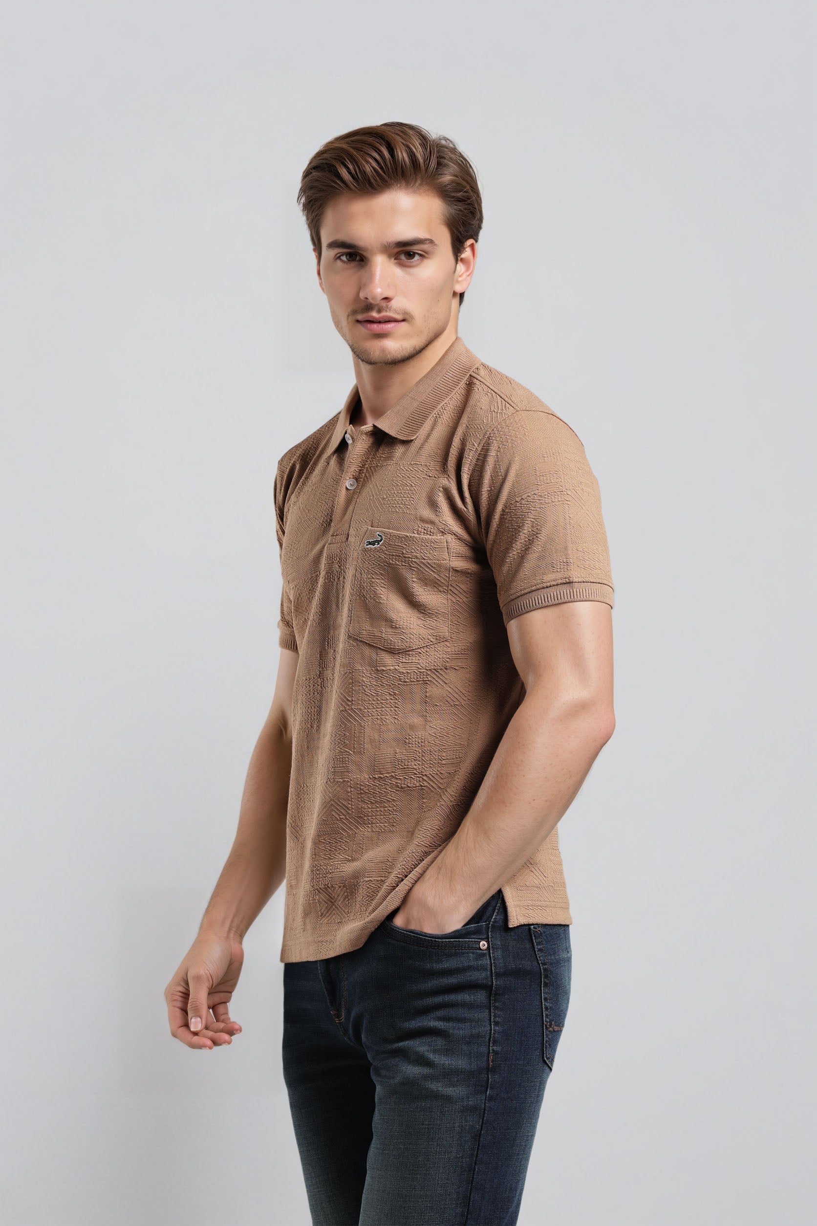 Man wearing a brown polo shirt and dark jeans on a light gray background