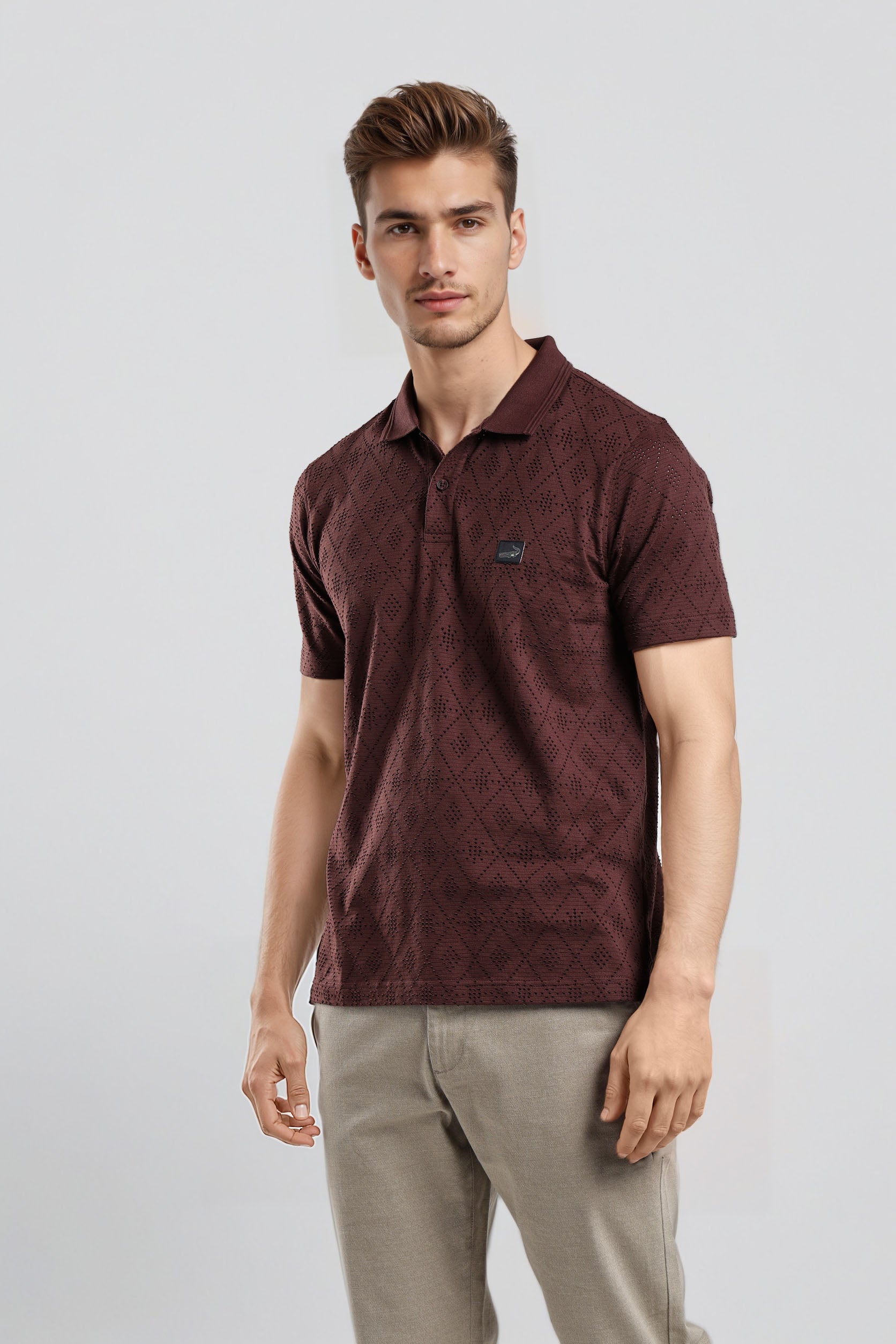 Man wearing a maroon polo shirt and beige pants on a light gray background