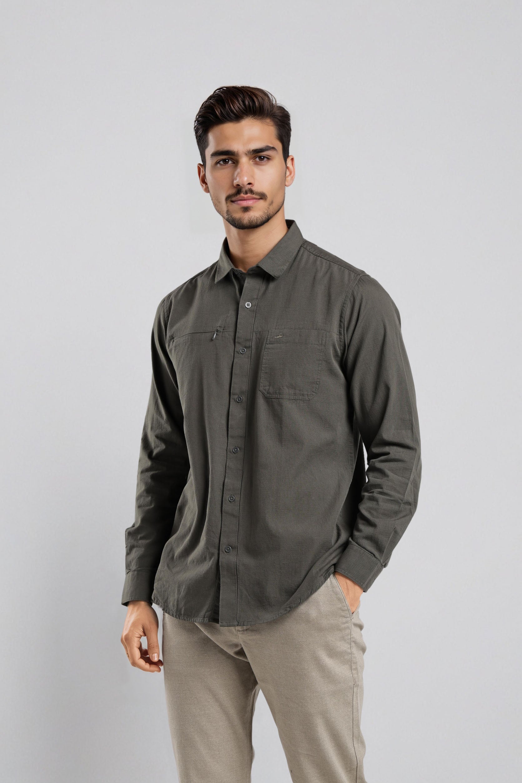 Man wearing a dark gray button-up shirt and beige pants on a light gray background