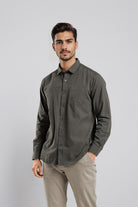 Man wearing a dark gray button-up shirt and beige pants on a light gray background