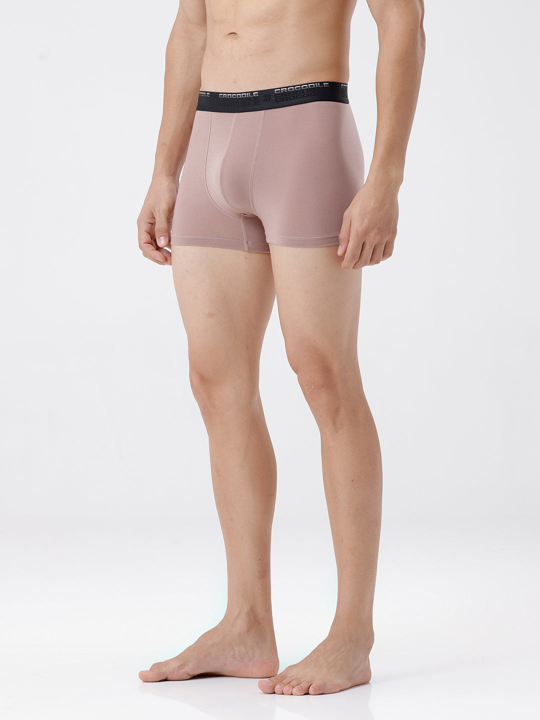 Person wearing a pair of beige boxer briefs with a black waistband on a white background