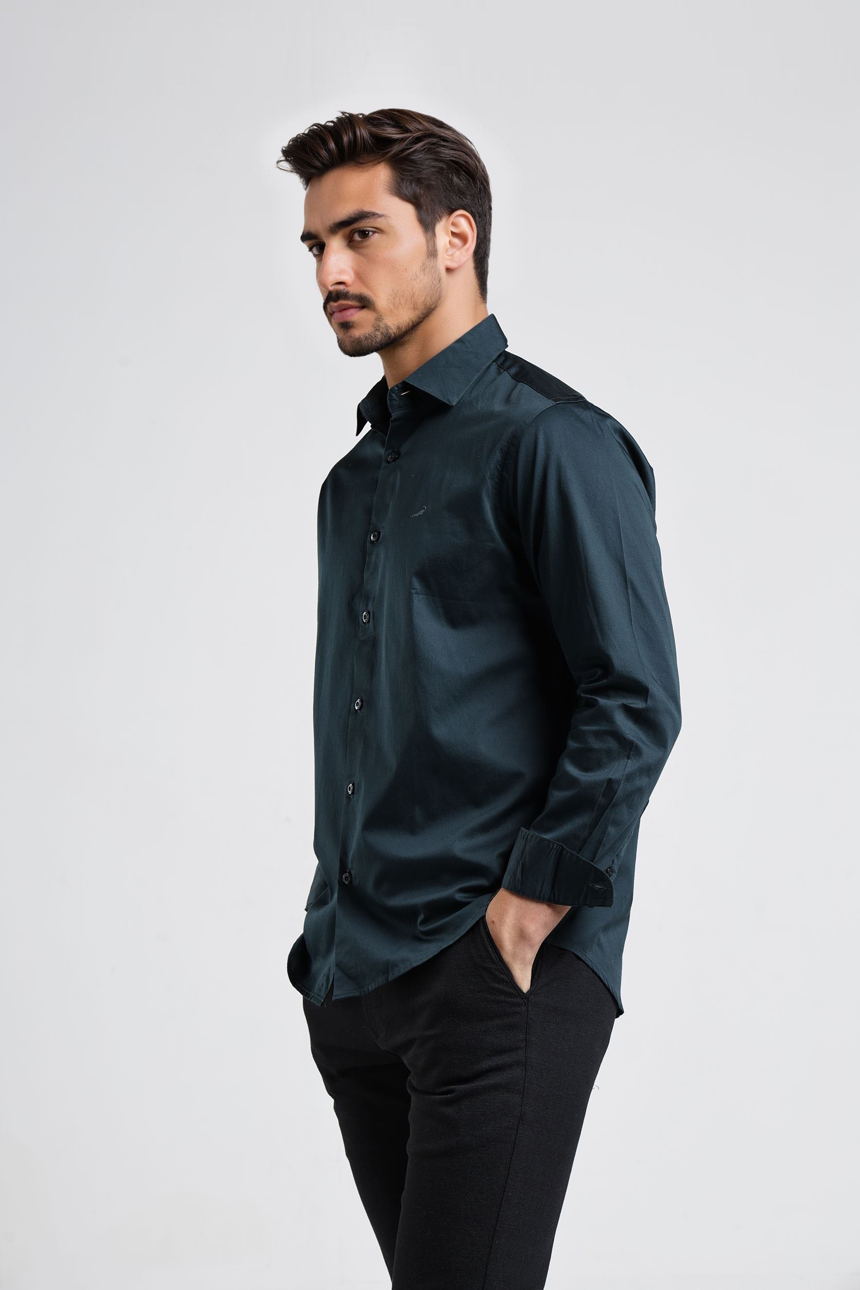 Man wearing a dark green shirt and black pants on a white background