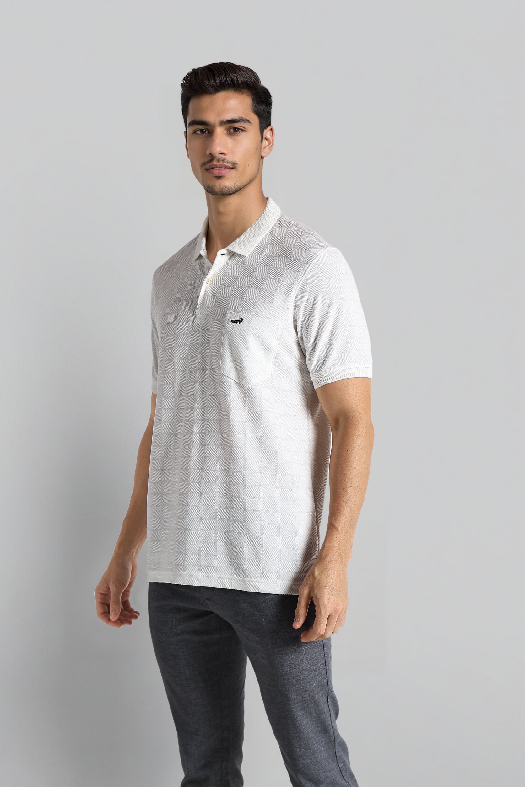 Man wearing a white polo shirt with a small logo on a gray background