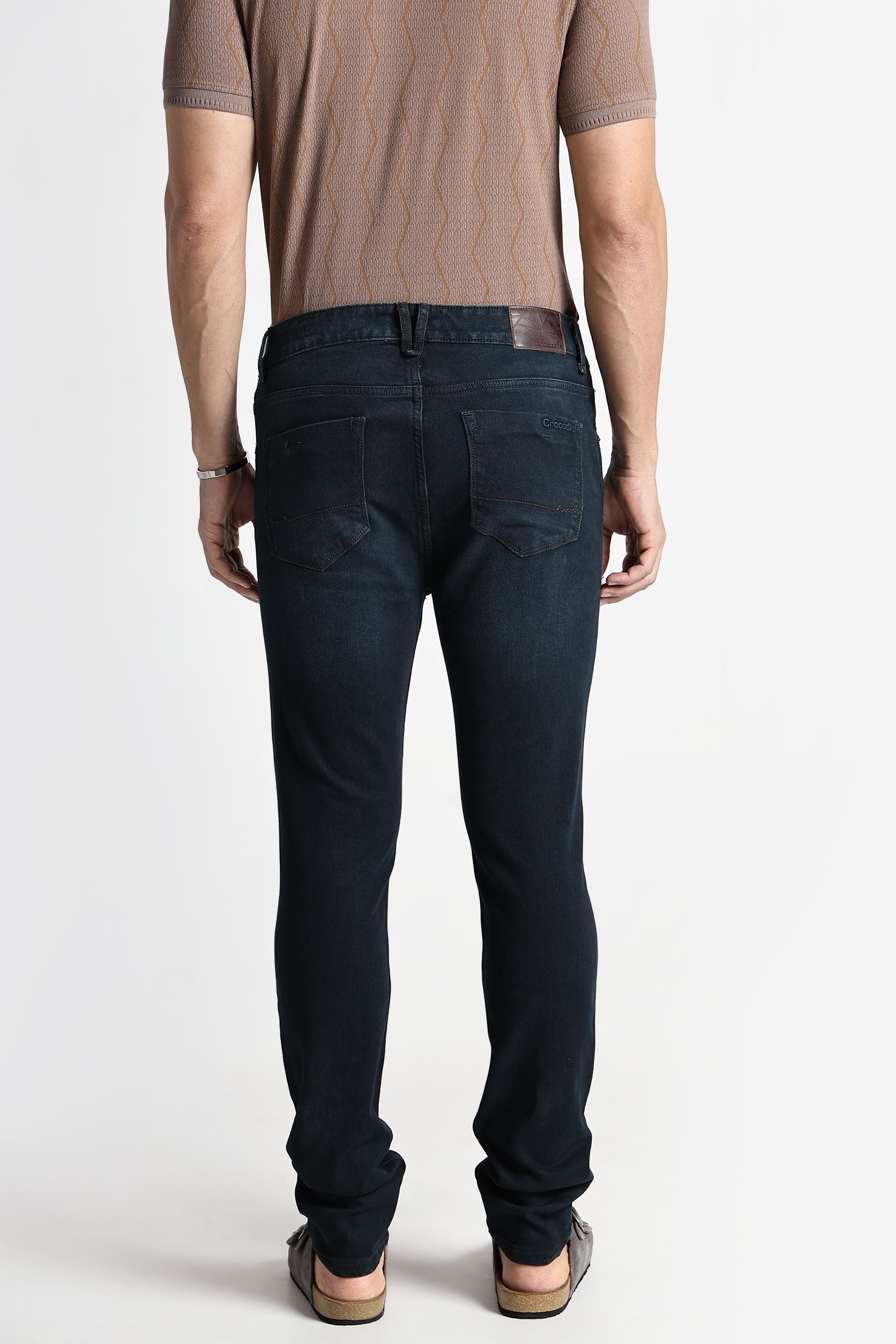 Person wearing dark jeans and a brown shirt on a white background