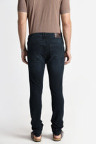 Person wearing dark jeans and a brown shirt on a white background