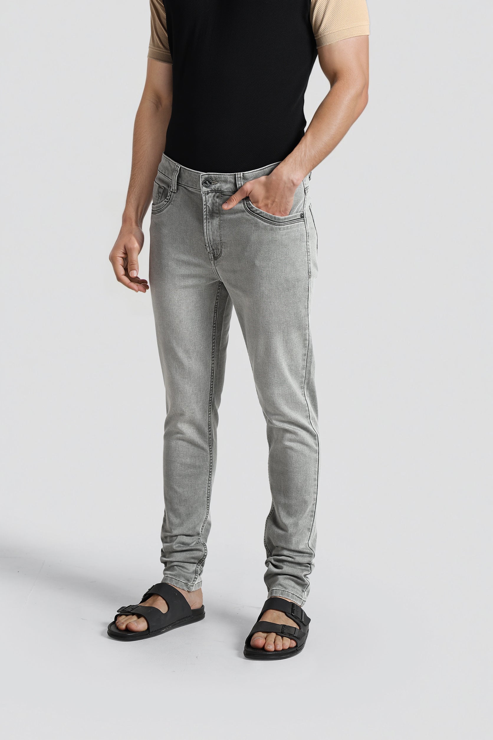 Person wearing gray jeans and black sandals on a light gray background