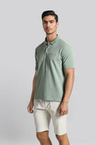 Man wearing a green polo shirt and white shorts on a gray background