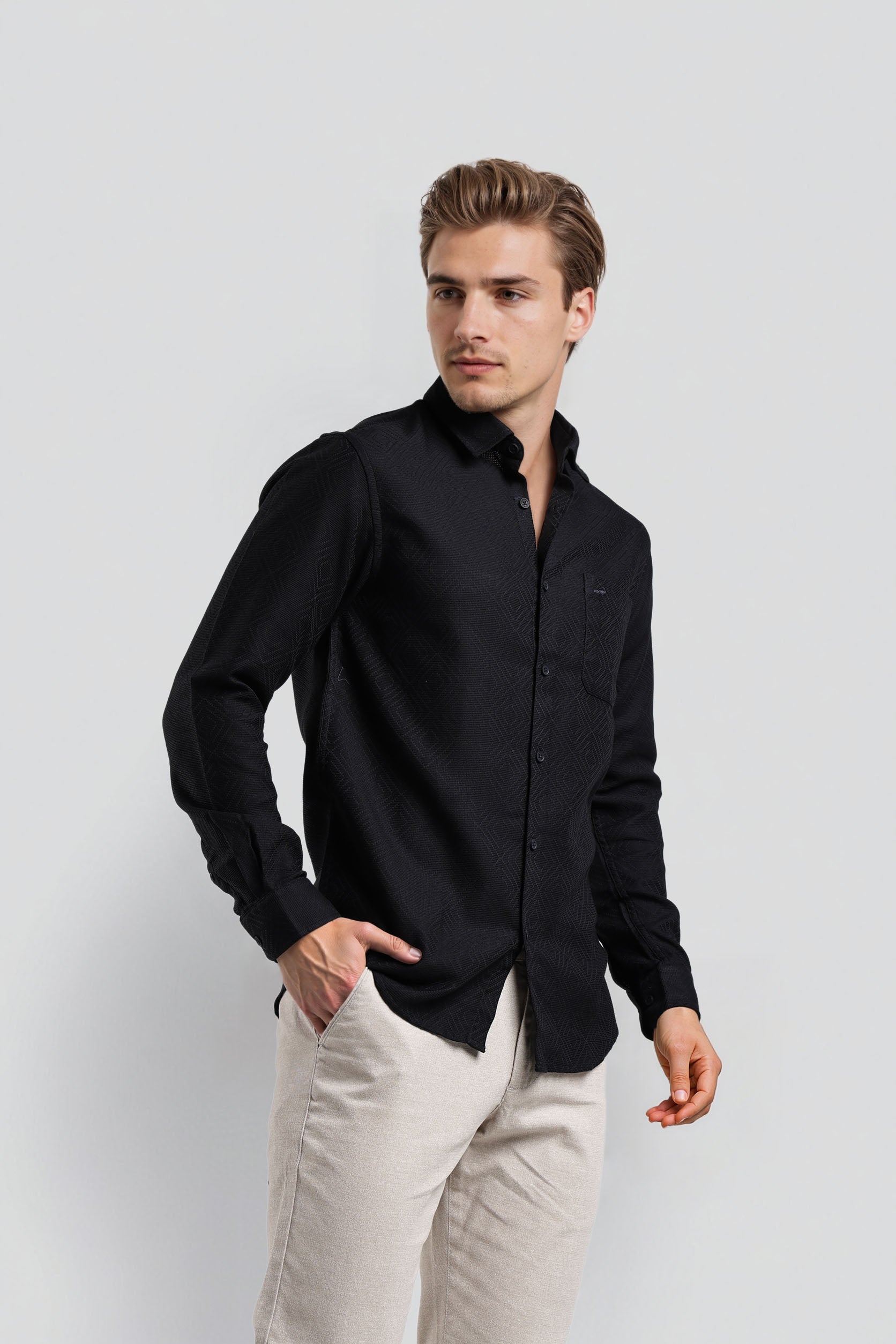 Man wearing a black shirt and light-colored pants against a white background