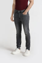 Person wearing dark gray jeans and white sneakers on a white background