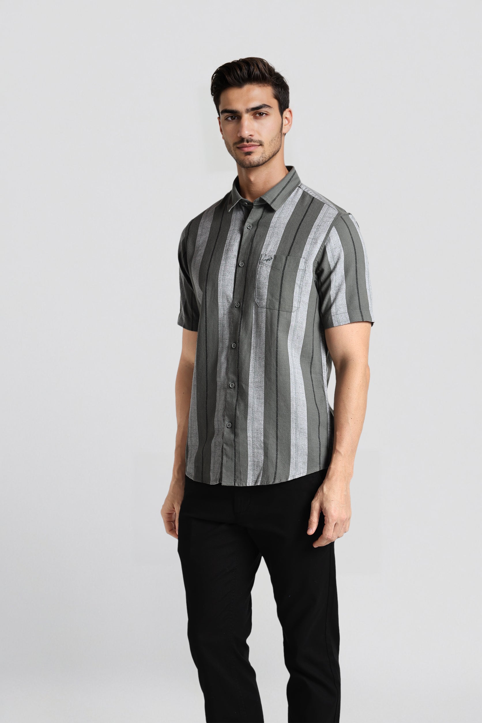 Man wearing a striped shirt and black pants on a light gray background