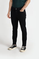 Person wearing black jeans and black sneakers on a white background