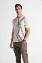 Man wearing a beige t-shirt with graphic design and cargo pants on a white background