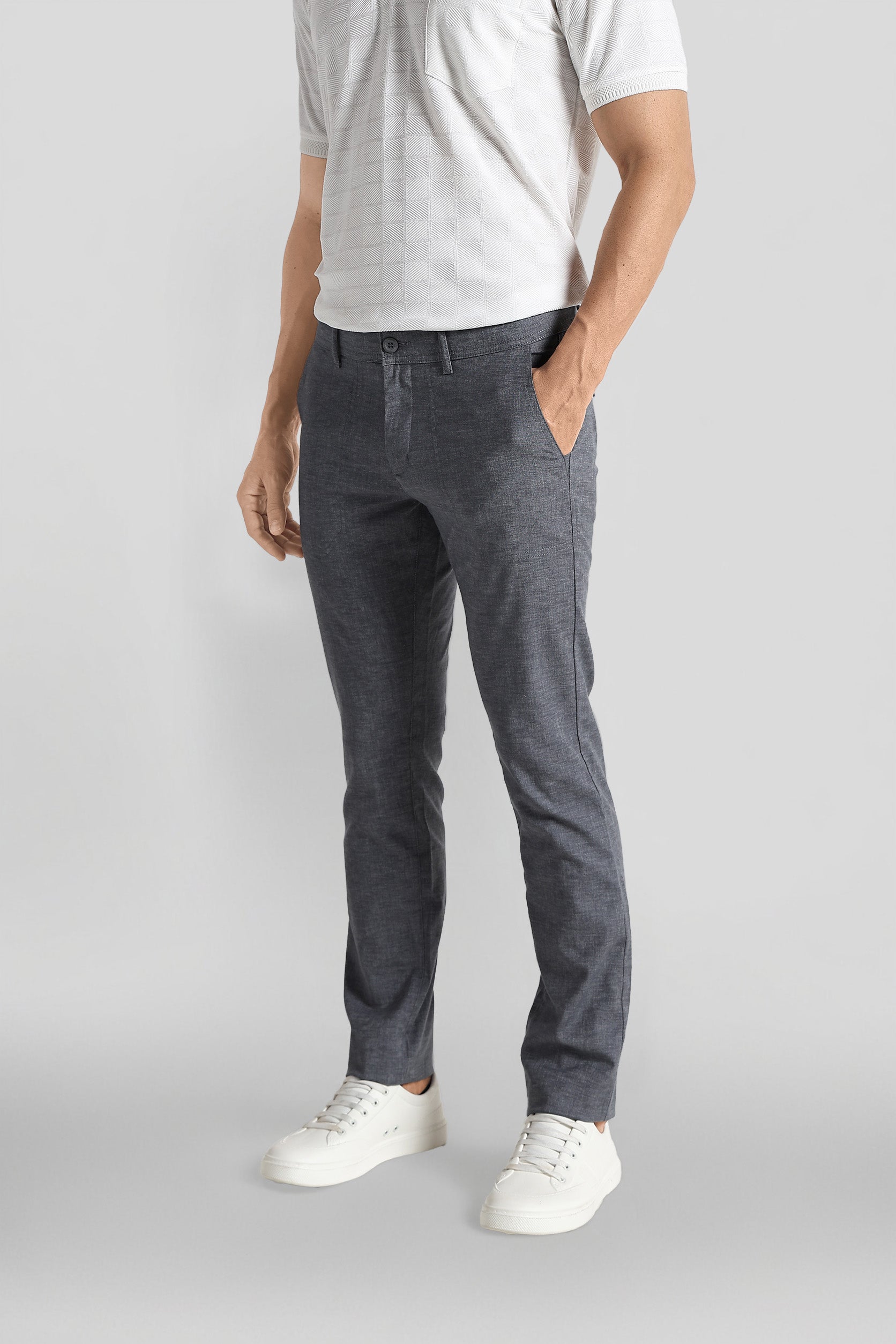 Person wearing gray pants and white shoes on a light gray background