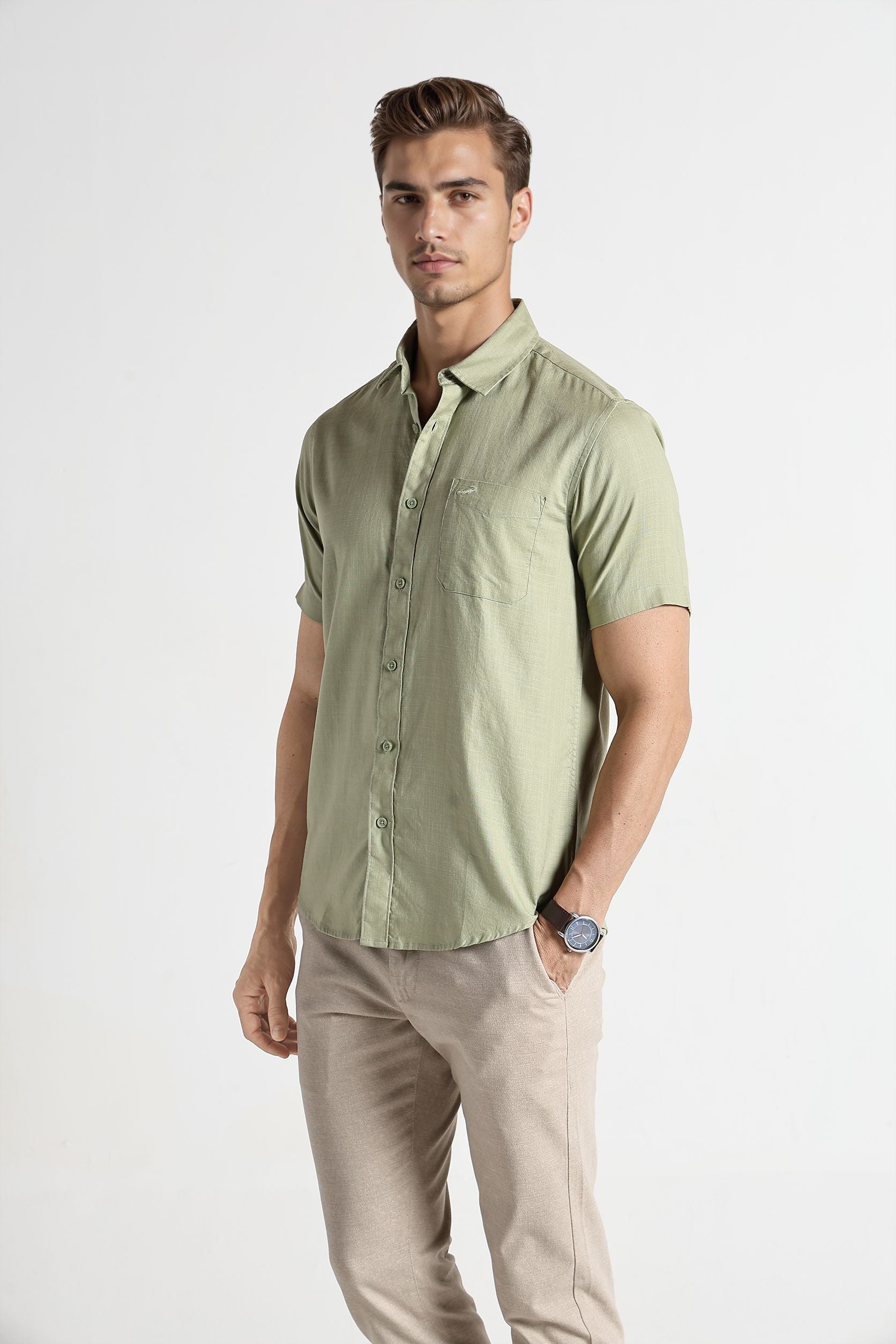 Man wearing a light green shirt and beige pants on a white background