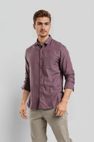 Man wearing a purple shirt and beige pants against a light gray background