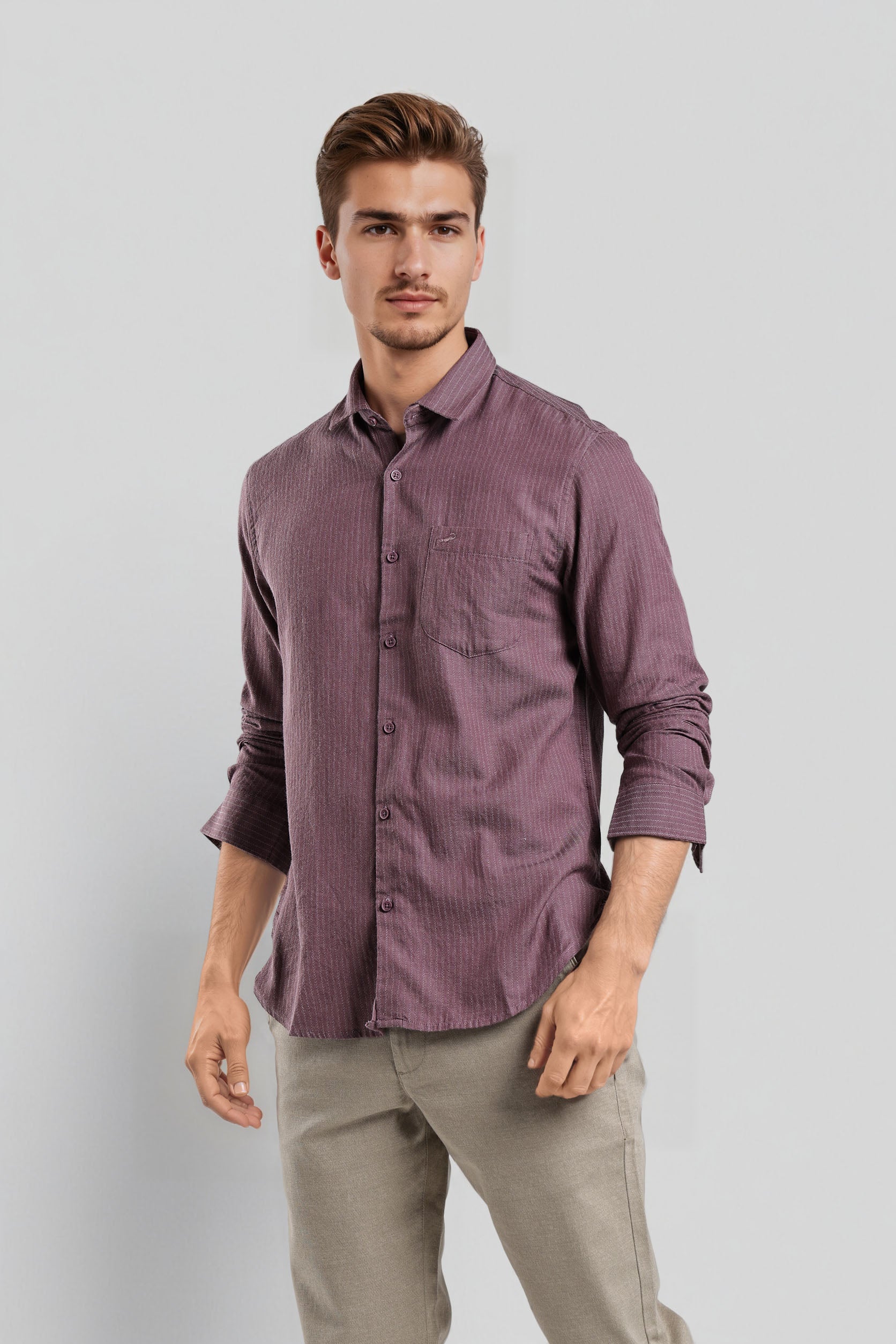 Man wearing a purple shirt and beige pants against a light gray background