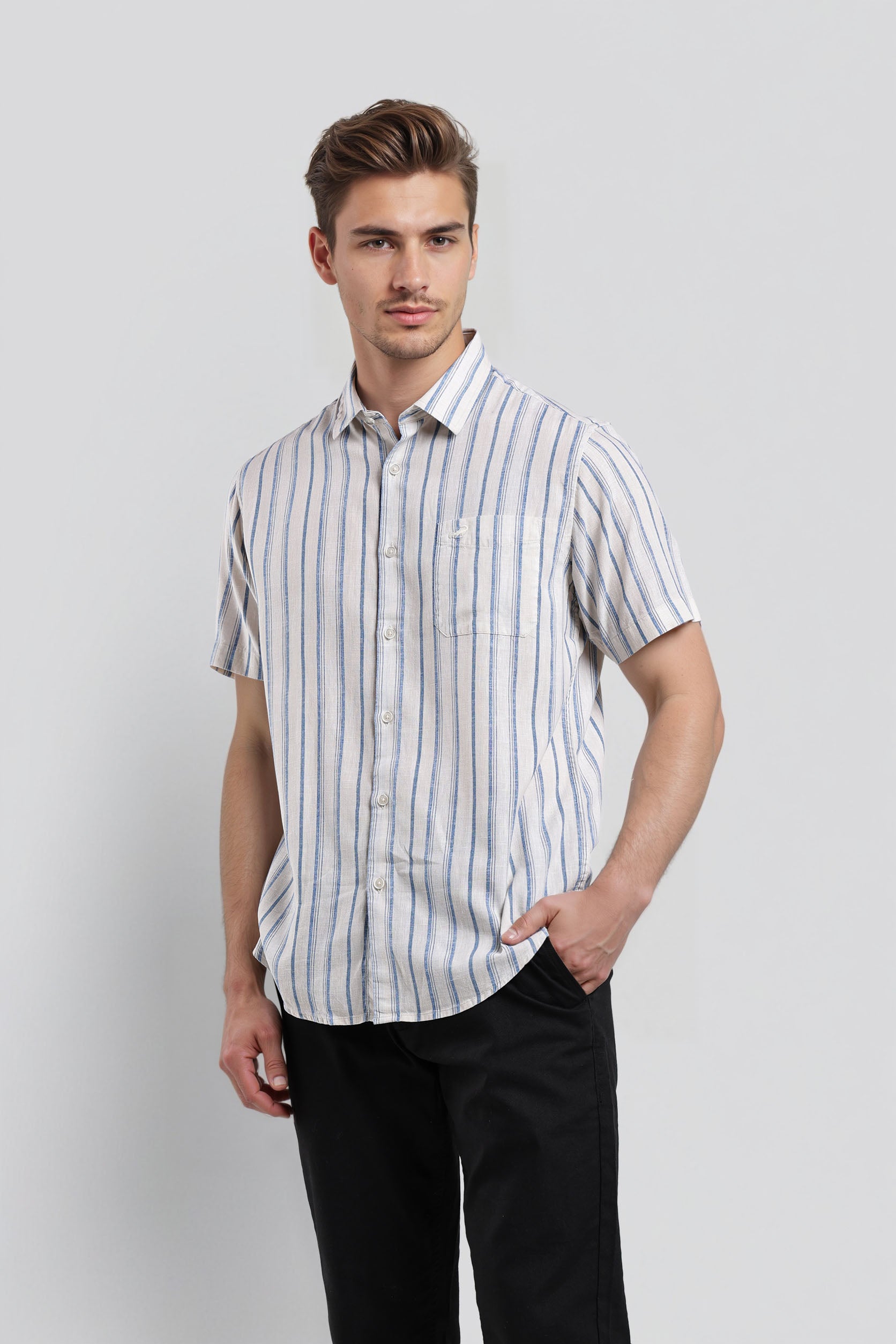 Man wearing a striped shirt and black pants on a light gray background