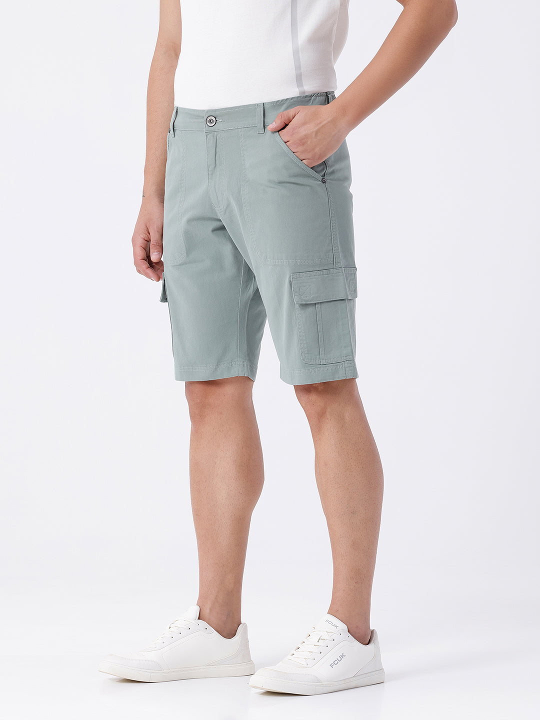 Man wearing a olive garment dyed cargo shorts in olive on a light gray background