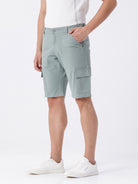 Man wearing a olive garment dyed cargo shorts in olive on a light gray background